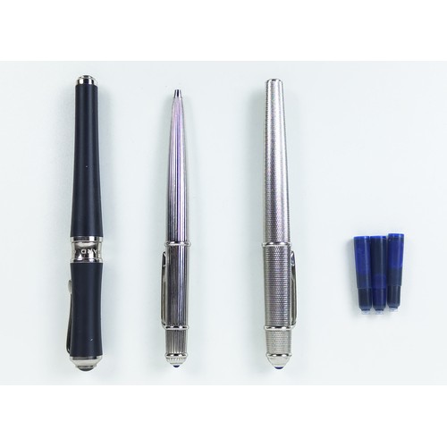 120A - TWO CARTIER BALLPOINT WHITE METAL PENS, comprising one with an engine turned case, blue cabochon ter... 