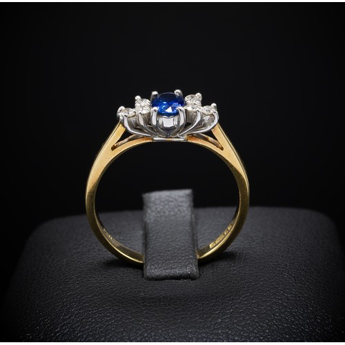 137 - AN 18CT YELLOW GOLD SAPPHIRE AND DIAMOND DRESS RING, the central oval mixed cut sapphire flanked by ... 