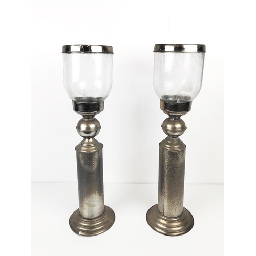 196 - STORM CANDLESTICKS, a pair, with glass shades, with a hammered metal column base, each 62cm H x 17cm... 