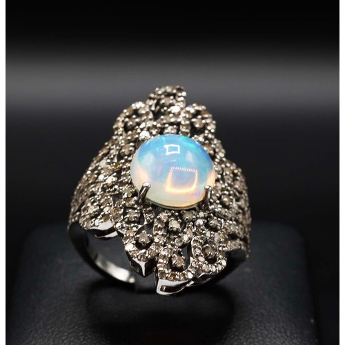 28 - LARGE DRESS RING IN SILVER SET, with a central round cabochon opal and diamond set filigree surround... 