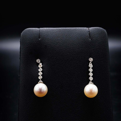 64A - A PAIR OF 9CT WHITE GOLD CULTURED PEARL DROP EARRINGS, each with diamond set bales, diamonds with a ... 