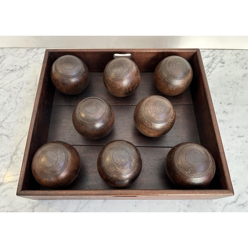 140 - BOWLS, a set of eight, vintage lignum vitae bowls in an old mahogany tray, tray 51cm x 46cm x 12cm.