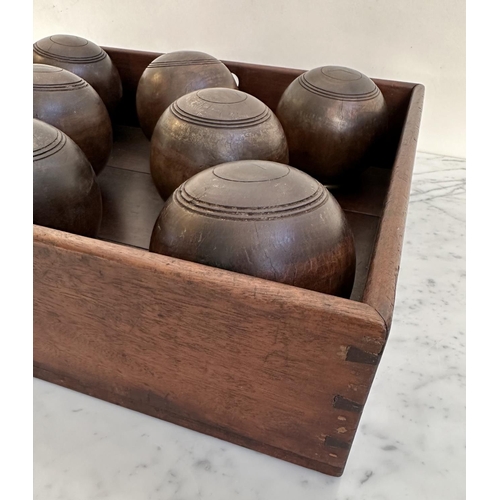 140 - BOWLS, a set of eight, vintage lignum vitae bowls in an old mahogany tray, tray 51cm x 46cm x 12cm.