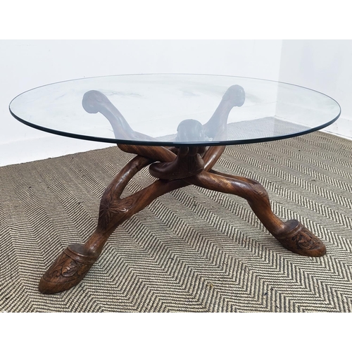 176 - LOW TABLE, circular glass top on shaped and carved hardwood supports, 50cm H x 100cm D.