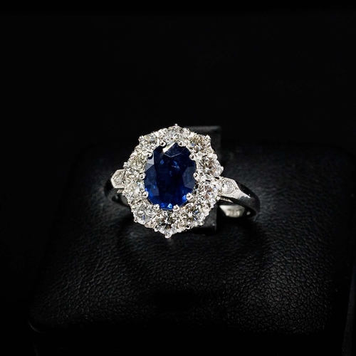 54 - PLATINUM RING SET WITH AN OVAL SAPPHIRE, a halo of RBC diamonds and diamond set shoulders, sapphire ... 