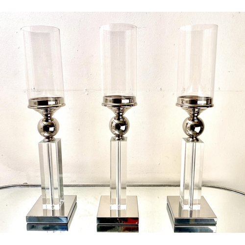 529 - CANDLESTICKS, a set of three, chrome and glass, 53cm H (3)