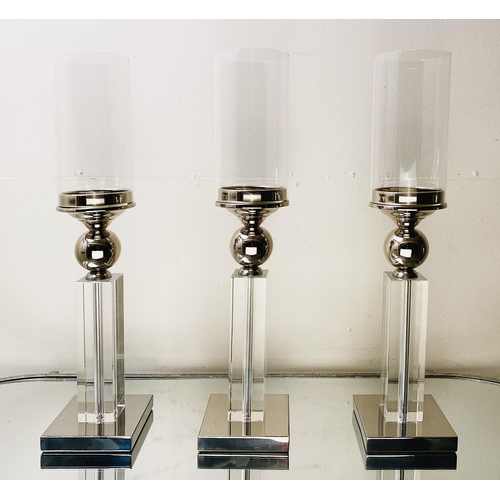 529 - CANDLESTICKS, a set of three, chrome and glass, 53cm H (3)