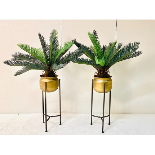 447 - FAUX CYCAD PLANTS, a pair, in gilt metal planters on metal stands, 100cm H x 50cm x 50cm. (2)