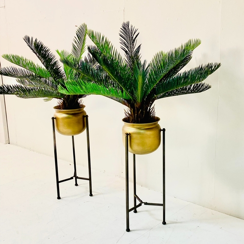 447 - FAUX CYCAD PLANTS, a pair, in gilt metal planters on metal stands, 100cm H x 50cm x 50cm. (2)