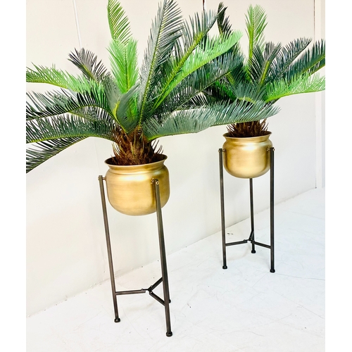 447 - FAUX CYCAD PLANTS, a pair, in gilt metal planters on metal stands, 100cm H x 50cm x 50cm. (2)