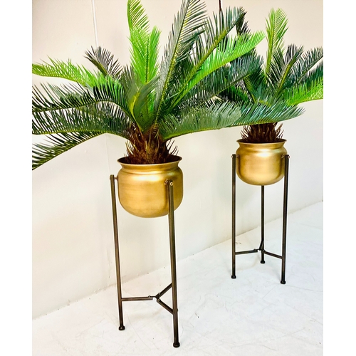 447 - FAUX CYCAD PLANTS, a pair, in gilt metal planters on metal stands, 100cm H x 50cm x 50cm. (2)