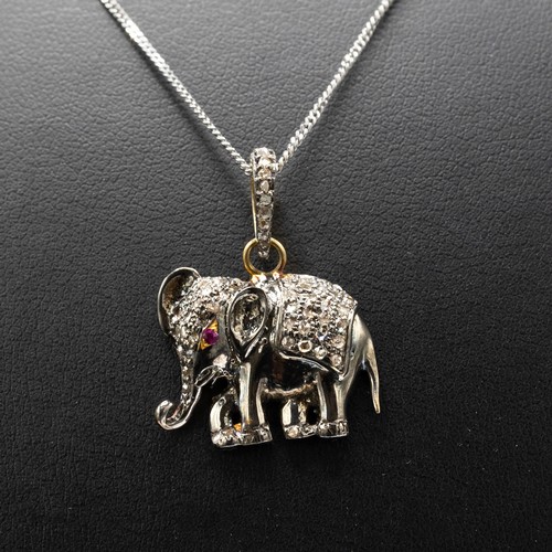 11 - AN ELEPHANT PENDANT IN YELLOW AND WHITE METAL SET WITH A RUBY EYE AND R/C DIAMONDS on a silver chain... 