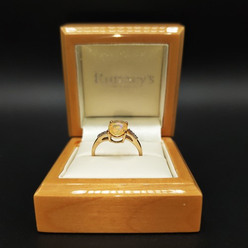 9 - A 9CT YELLOW GOLD OVAL-CUT YELLOW OPAL RING, with diamond-set twist shoulders, boxed.