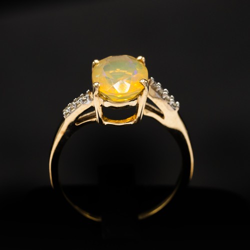 9 - A 9CT YELLOW GOLD OVAL-CUT YELLOW OPAL RING, with diamond-set twist shoulders, boxed.