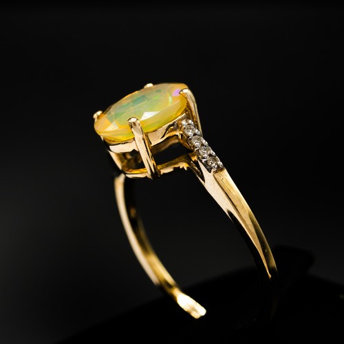 9 - A 9CT YELLOW GOLD OVAL-CUT YELLOW OPAL RING, with diamond-set twist shoulders, boxed.