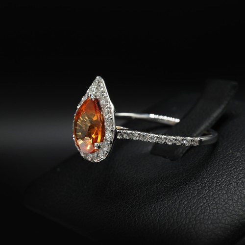 26 - 18ct white gold ring set with a pear shaped orange sapphire surrounded by RBC diamonds, with further... 