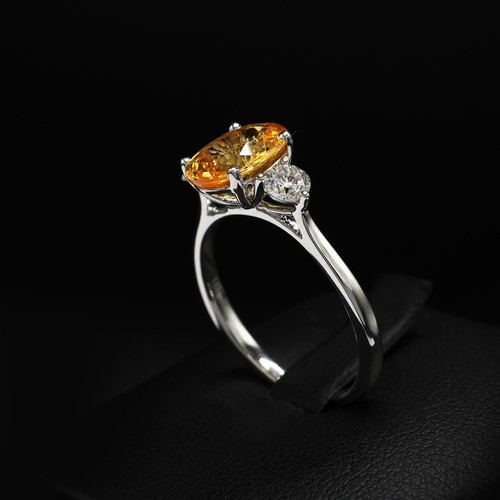 24 - 18ct white gold trilogy ring set with a central oval-cut orange sapphire flanked by RBC diamonds. Sa... 