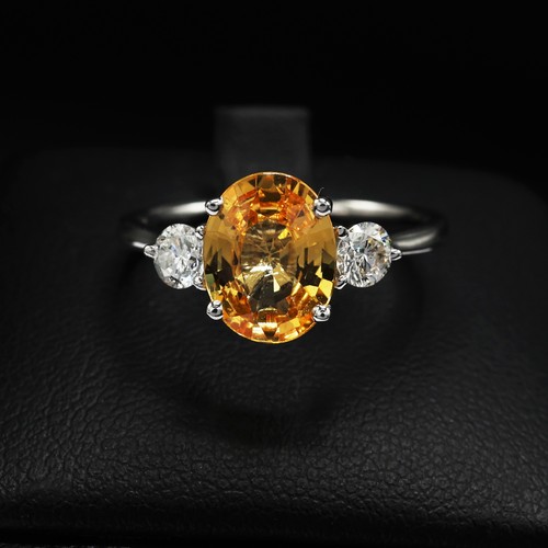 24 - 18ct white gold trilogy ring set with a central oval-cut orange sapphire flanked by RBC diamonds. Sa... 