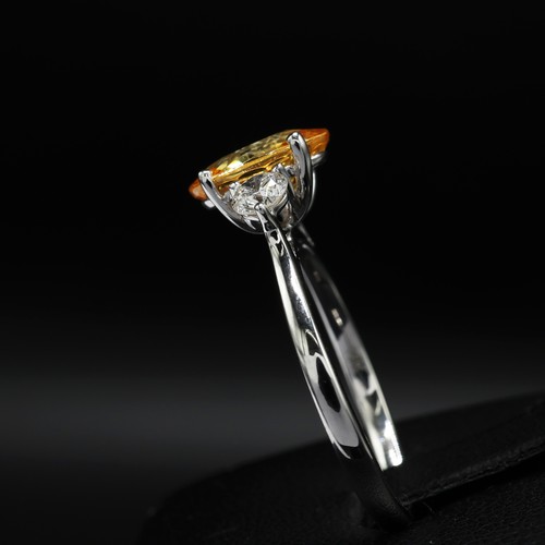 24 - 18ct white gold trilogy ring set with a central oval-cut orange sapphire flanked by RBC diamonds. Sa... 