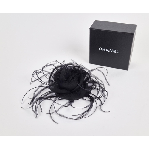 11 - CHANEL BROOCH, iconic black silk camellia with raw hem, ostrich feather at base, gold tone safety pi... 