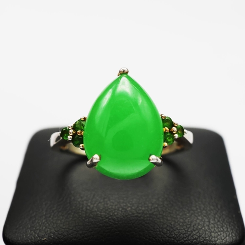 113 - A STERLING SILVER JADE AND PERIDOT DRESS RING, the pear shaped jade cabochon flanked to each side by... 