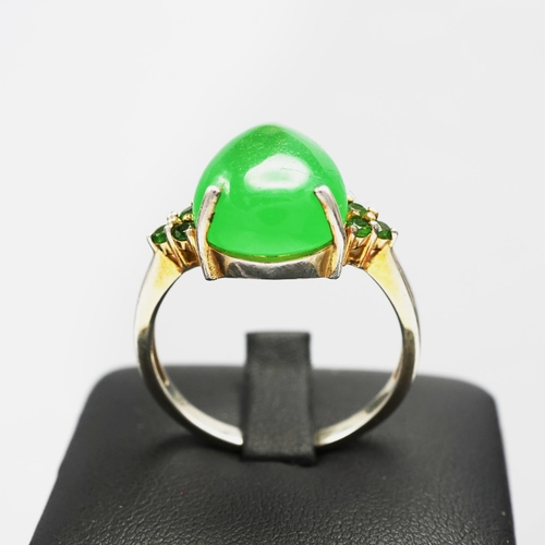 113 - A STERLING SILVER JADE AND PERIDOT DRESS RING, the pear shaped jade cabochon flanked to each side by... 