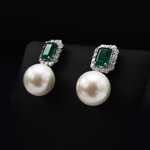 132 - A PAIR OF 18CT WHITE GOLD PEARL DROP EARRINGS, each set with a large emerald-cut emerald surrounded ... 