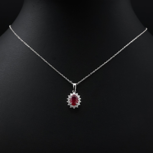 138 - 18ct white gold oval ruby and RBC diamond cluster pendant on an 18ct white gold chain, boxed. Ruby 0... 