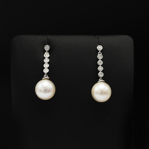 92 - A PAIR OF 9CT WHITE GOLD CULTURED PEARL DROP EARRINGS, each with diamond set bales, diamonds with a ... 