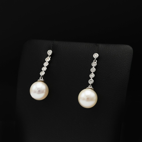 92 - A PAIR OF 9CT WHITE GOLD CULTURED PEARL DROP EARRINGS, each with diamond set bales, diamonds with a ... 