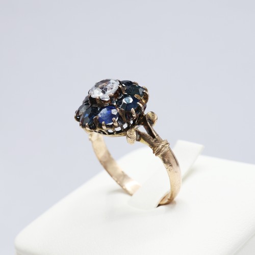 117 - A VICTORIAN YELLOW METAL WHITE AND BLUE SAPPHIRE DRESS RING, the central stone surrounded by eight m... 