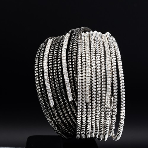 83 - AN 18CT WHITE AND BLACK GOLD DIAMOND SET CUFF BANGLE, formed of eighteen spiral twist bands, with fo... 