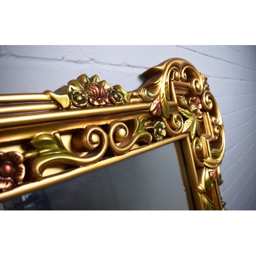 260 - LARGE GILT FRAMED WALL MIRROR WITH FLORAL FRAME. 128cm H x 168cm W.