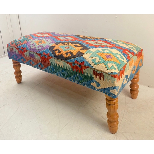 23 - HEARTH STOOL WITH KILIM UPHOLSTERY ON TURNED SUPPORTS. 52cm H x 123cm W x 50cm D.