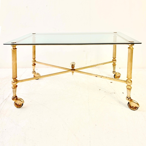 80 - REGENCY STYLE GILT METAL LOW TABLE. with a glass top on x-frame stretchered supports and castors.