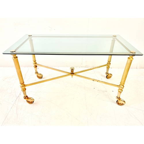 80 - REGENCY STYLE GILT METAL LOW TABLE. with a glass top on x-frame stretchered supports and castors.