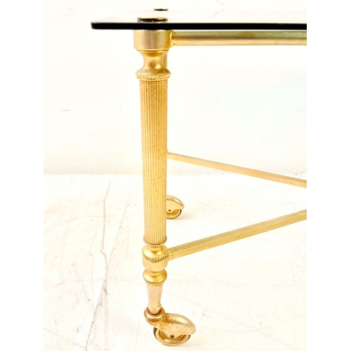80 - REGENCY STYLE GILT METAL LOW TABLE. with a glass top on x-frame stretchered supports and castors.