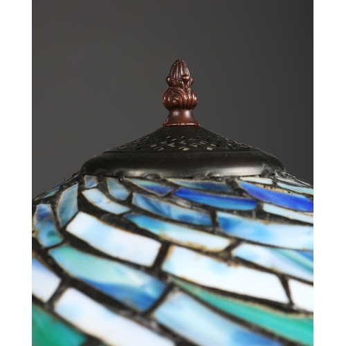 128 - TIFFANY STYLE TABLE LAMP. the shade with a swirling stylised foliage design, bronzed base, raised on... 