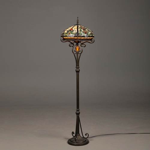 132 - TIFFANY STYLE FLOOR LAMP. the glass shade in a symmetrical stylised foliage design, raised on a scro... 