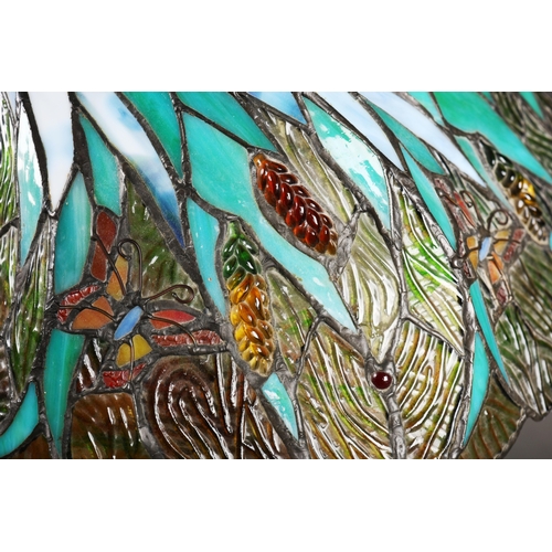 128 - TIFFANY STYLE TABLE LAMP. the shade with a swirling stylised foliage design, bronzed base, raised on... 
