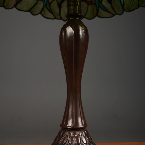 128 - TIFFANY STYLE TABLE LAMP. the shade with a swirling stylised foliage design, bronzed base, raised on... 