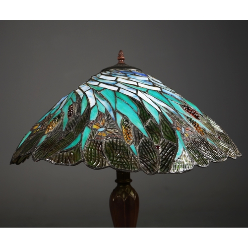 128 - TIFFANY STYLE TABLE LAMP. the shade with a swirling stylised foliage design, bronzed base, raised on... 