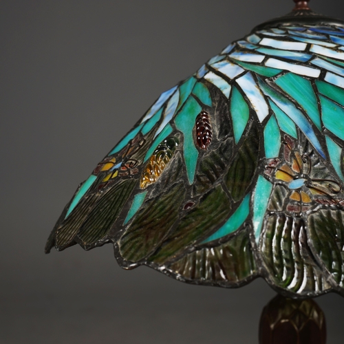 128 - TIFFANY STYLE TABLE LAMP. the shade with a swirling stylised foliage design, bronzed base, raised on... 