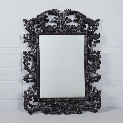 182 - A ROCOCO STYLE BLACK STAINED WALL MIRROR. having an acanthus carved frame, 116cm high, 83cm wide.