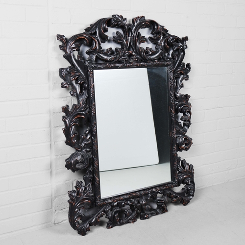 182 - A ROCOCO STYLE BLACK STAINED WALL MIRROR. having an acanthus carved frame, 116cm high, 83cm wide.