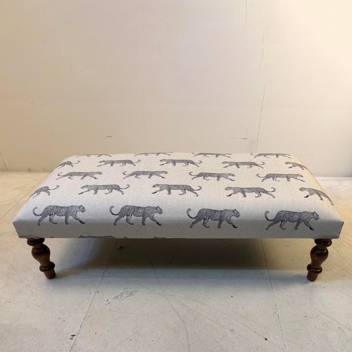 192 - LOW FOOTSTOOL IN LEOPARD PRINT UPHOLSTERY ON TURNED SUPPORTS. 38cm H x 100cm W x 50cm D.