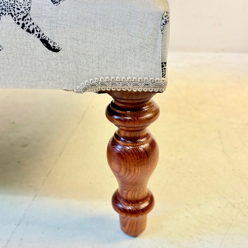 192 - LOW FOOTSTOOL IN LEOPARD PRINT UPHOLSTERY ON TURNED SUPPORTS. 38cm H x 100cm W x 50cm D.