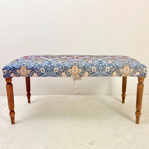 224 - FOOTSTOOL IN WILLIAM MORRIS STYLE UPHOLSTERY ON REEDED SUPPORTS. 45cm H x 100cm W x 38cm D.
