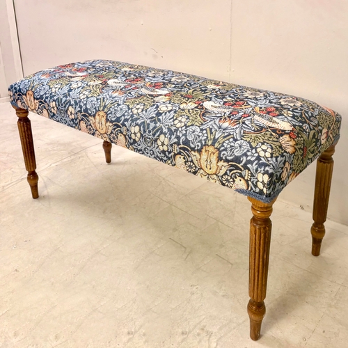 224 - FOOTSTOOL IN WILLIAM MORRIS STYLE UPHOLSTERY ON REEDED SUPPORTS. 45cm H x 100cm W x 38cm D.