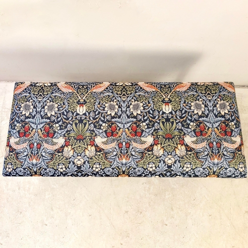224 - FOOTSTOOL IN WILLIAM MORRIS STYLE UPHOLSTERY ON REEDED SUPPORTS. 45cm H x 100cm W x 38cm D.